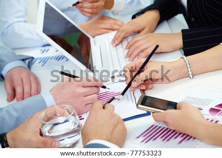 Image of human hands working with papers at meeting