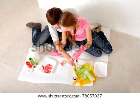 Young couple preparing paints while sitting on floor in new flat