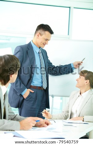 A business man showing something on a whiteboard and looking at colleague