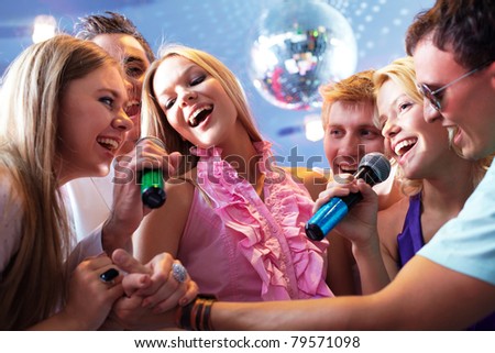 Portrait of joyous guys and girls singing at party together