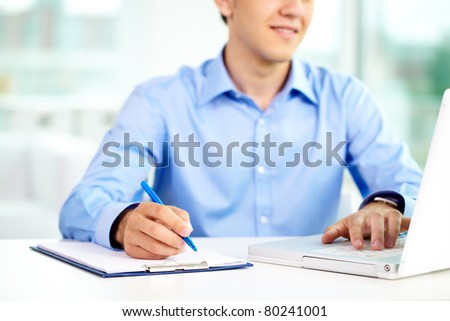 Image of successful businessman typing and making notes