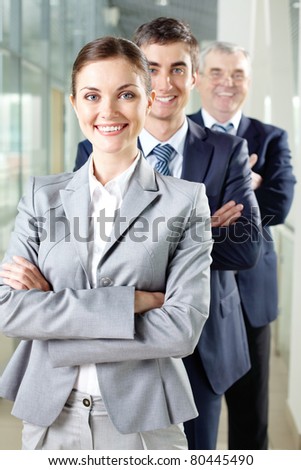 Smiling businesswoman looking at camera with two men behind