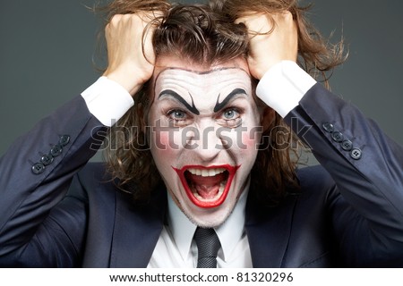 Portrait of frustrated businessman with theatrical makeup tearing hair