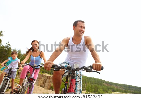 Sportive man on bike in front of his wife and son