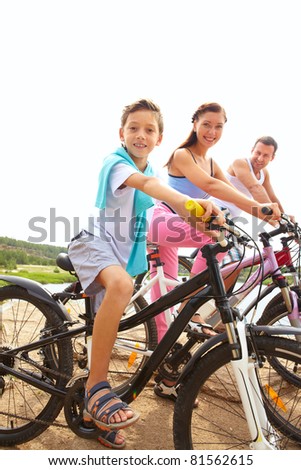 Portrait of family of three on bikes looking at camera and smiling