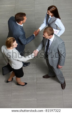 Four business partners handshaking while striking deal