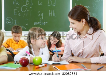 Portrait of smart girl and her teacher looking at each other at lesson in classroom