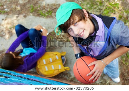 Portrait of happy guy with ball looking at camera in the park
