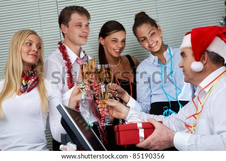 Image of cheering associates congratulating ceo in Santa cap at corporate party