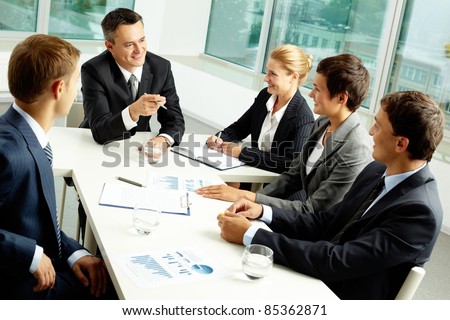 Image of confident colleagues communicating with their boss at meeting