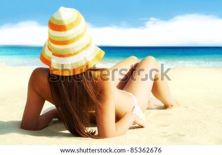 Image of female in white bikini sunbathing on sandy beach during vacation