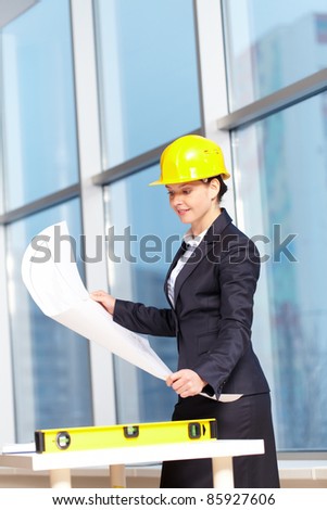 A young woman architect in helmet examining a plan