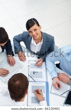 Above angle of beautiful secretary looking at camera in working environment