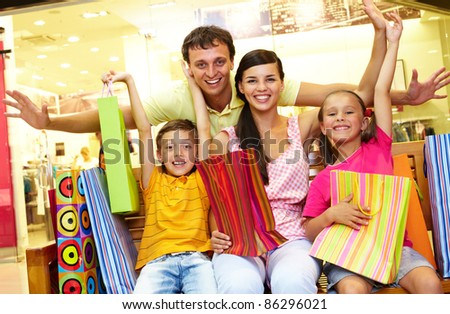 Portrait of joyful family sitting in store with plenty of shopping bags