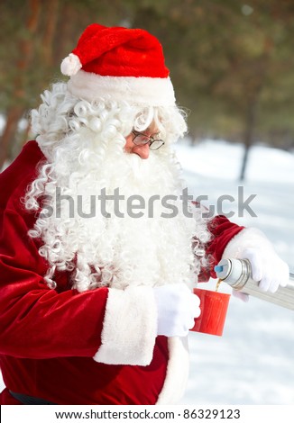 Santa Claus drinking hot tea in winter forest
