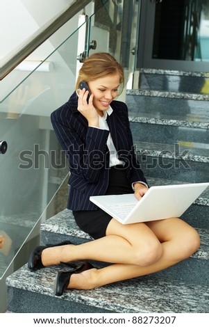Image of smart businesswoman working on staircase with laptop and calling