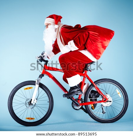 Photo of Santa Claus with red sack riding bike