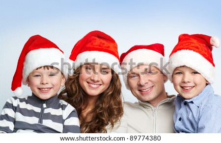 Portrait of four happy family members in Santa caps looking at camera with smiles