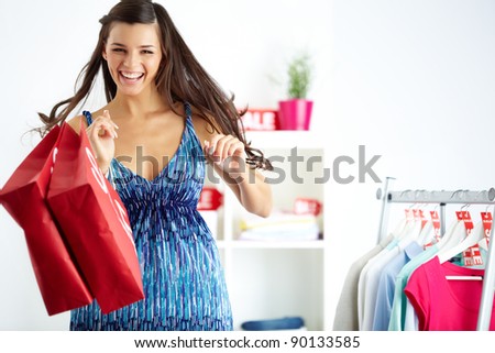 Portrait of happy shopper with bags laughing in clothing department