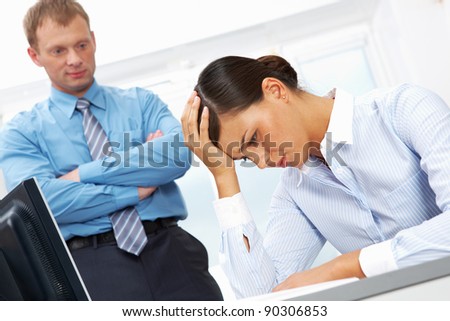 Portrait of young employee having trouble or headache with her boss at background