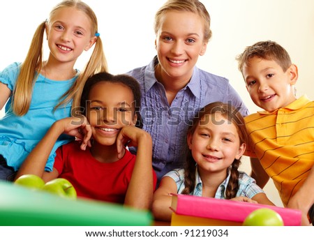 Portrait of smart schoolchildren and their teacher looking at camera in classroom
