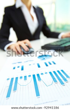Image of business paper on background of female hands pushing keys of a computer mouse and keyboard
