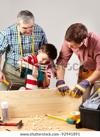 A boy working with drill under his father and grandpa?s supervision