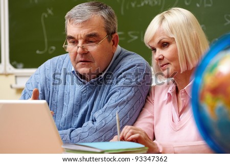 Portrait of mature man and aged female working with laptop during training course