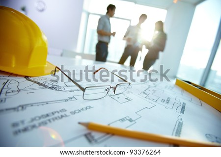 Image of engineering objects on workplace with three partners interacting on background