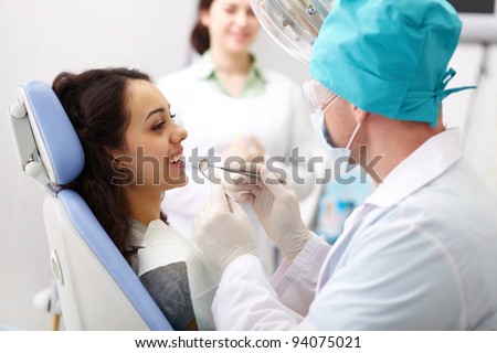 Young female patient receiving dental care from a friendly doctor and his assistant