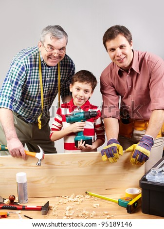 Vertical shot of three multigenerational guys working in a woodshop and smiling at camera