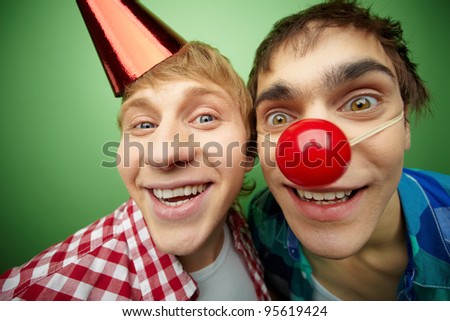 Two crazy guys making faces at camera on foolÃ¢Â?Â?s day, isolated on green background