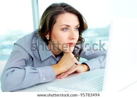 Pensive business woman looking at the screen of computer