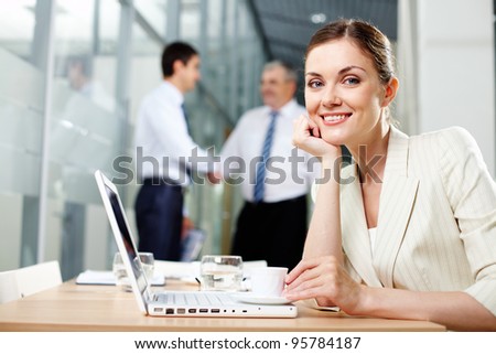 Pretty business lady working on a laptop while her male colleagues discussing business project