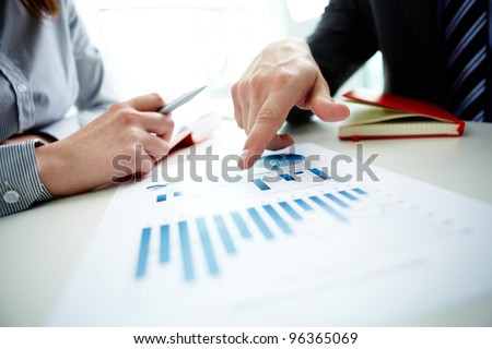 Image of male hand pointing at business document during discussion at meeting