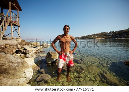Young man looking at camera while standing in water on southern resort