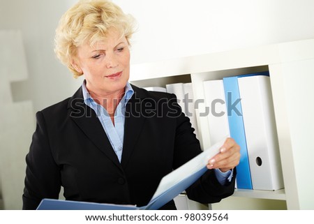 Portrait of middle aged businesswoman reading paper in office