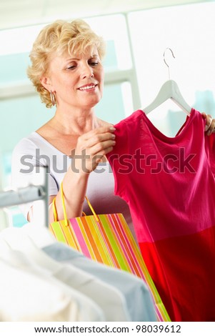 Portrait of middle aged woman choosing new tanktop in clothing department