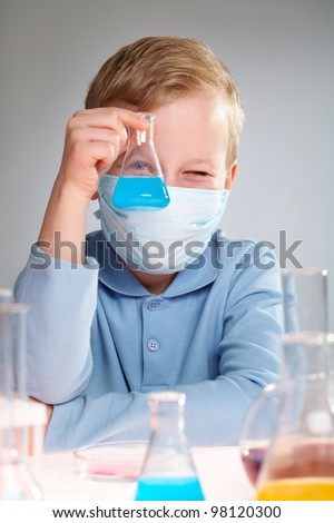 A little boy pouring liquid into a flask and looking at it