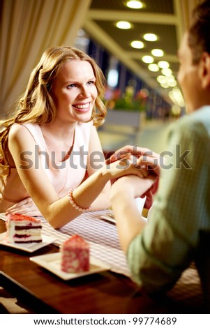 A young happy woman sitting in restaurant and looking at her boyfriend
