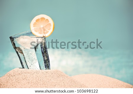 Cold Drink With Ice And A Slice Of Lemon On The Beach On A Hot Summer Day
