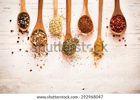 Spices in wooden spoons on white wooden background