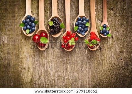 Berries in wooden spoons on wood texture