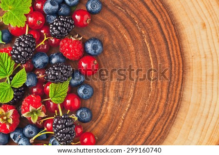 Fresh juicy berries with green leaves on wood texture