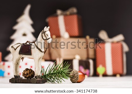 Christmas horse with spruce branches and fir cone closeup on dark background with gifts