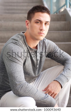 portrait of a handsome young man sitting on the steps inside a building