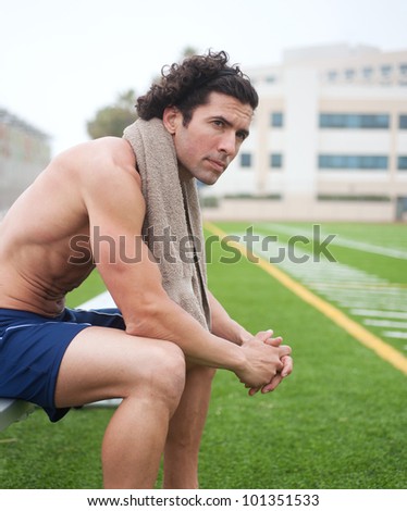 tired athletic male runner sitting in a stadium