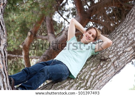 portrait of a young male relaxing on a tree outside in a park