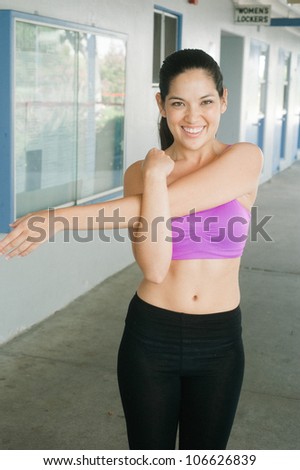 asian, female athletic trainer stretching outside