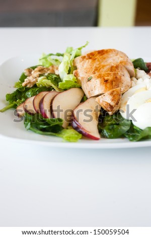 plate of fresh chopped grilled chicken salad on a white background